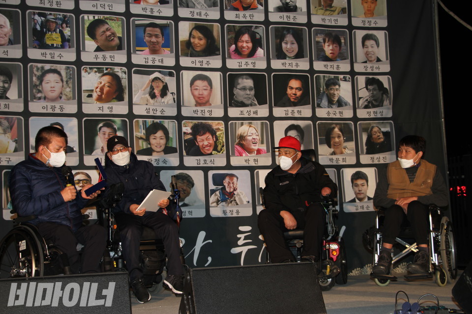 26일 오후 7시, 정부세종청사 보건복지부 앞에서 제1회 탈시설장애인상 시상식이 열렸다. 권달주 전국장애인차별철폐연대 상임공동대표가 상패에 적힌 글을 읽고 있다. 왼쪽부터 권달주 대표, 김동림 김포장애인야학 교감, 탈시설장애인상을 수상한 신정순·한태섭 씨의 모습. 사진 이가연