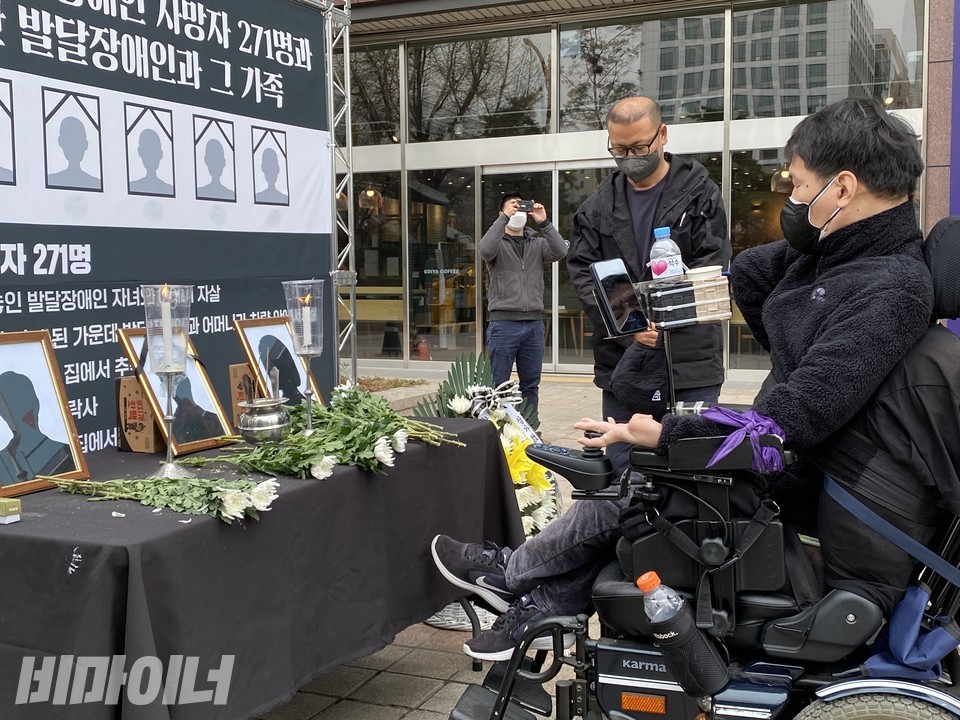 한 휠체어 이용 장애인이 추모단상 앞에서 헌화를 한 뒤 기도하고 있다. 사진 이가연