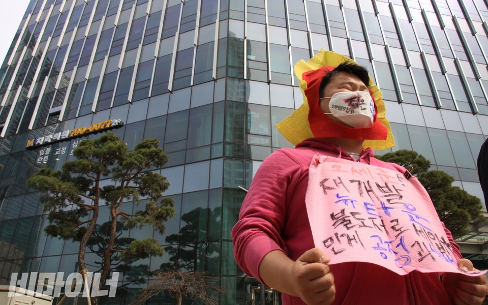 한 기자회견 참가자는 ‘오세훈! 재개발 뉴타운 불도저로 세입자 민 게 공정과 상생인가’라는 피켓을 상의에 붙였다. 참가자 뒤로 보이는 아파트는 24억~62억에 거래되고 있다. 사진 하민지