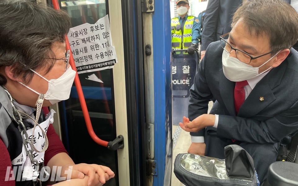 이종성 의원이 600번 버스로 찾아와 쇠사슬로 몸을 묶은 이형숙 회장과 대화를 나누고 있다. 이 회장이 “장애계가 세 달간 끊임없이 오 후보에게 면담을 요청했다”고 말하자 이 의원은 “시민에게 불편을 주지 말고 면담부터 하자”고 말했다. 사진 하민지