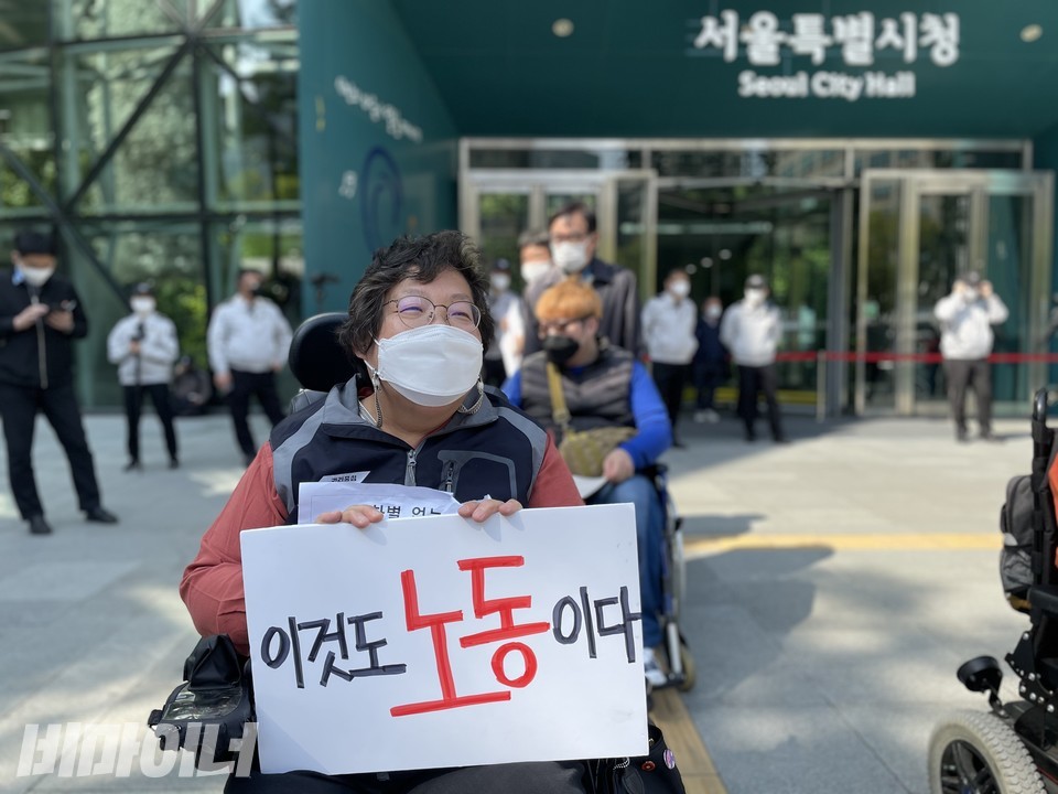 이형숙 서울시협의회 회장이 시청 정문 앞에서 '이것도 노동이다'라는 피켓을 들고 있다. 경찰들이 시청 정문 앞을 막아섰다. 사진 하민지