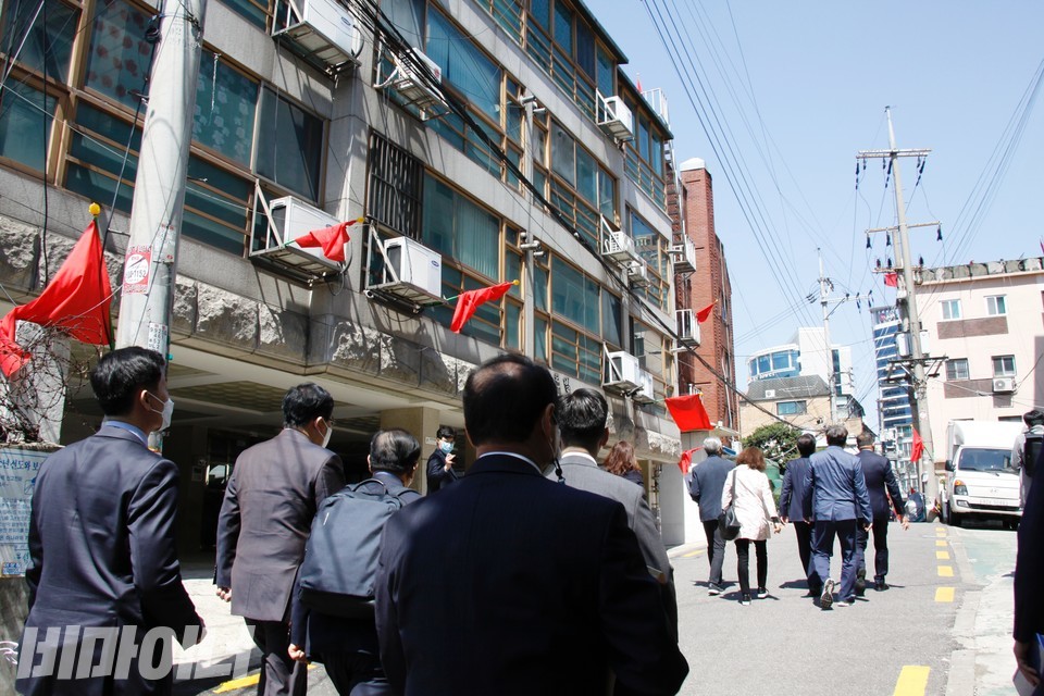 동자동 건물 곳곳에 영문을 알 수 없는 빨간 깃발이 꽂혀있고, 국회의원과 소유주들이 걸어가고 있다. 사진 이가연 