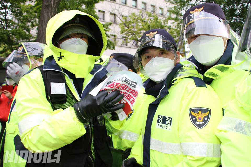 경찰이 방패에 붙은 피켓을 떼서 손으로 구기고 있다. 사진 강혜민