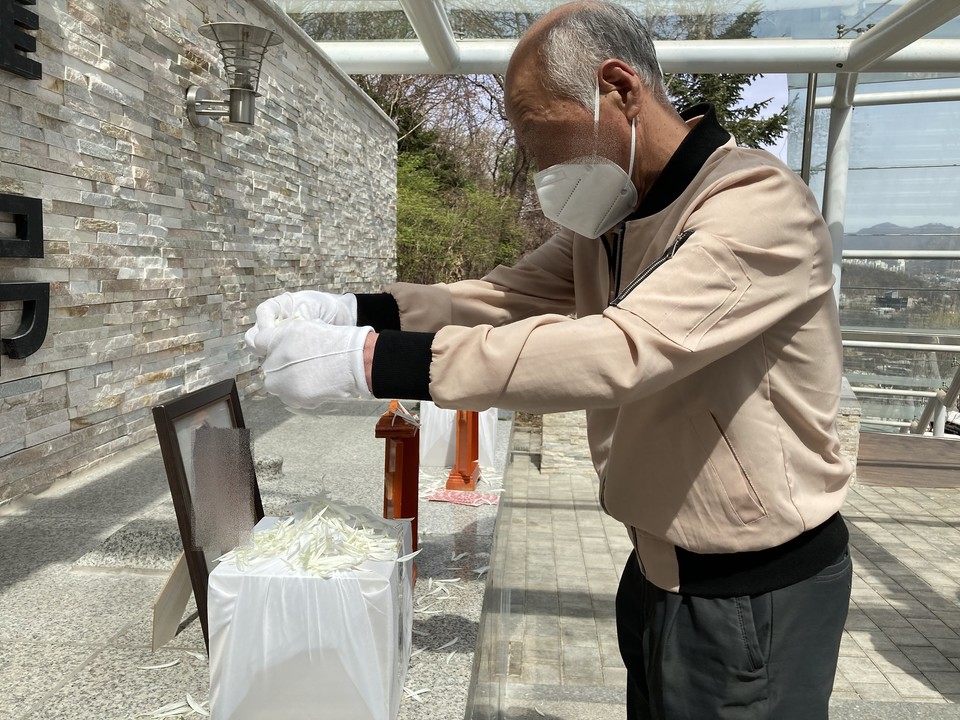 ㄴ 님의 유골함에 국화꽃잎을 뿌리고 있는 이웃 주민. 사진 나눔과나눔