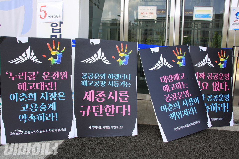 단식농성장 옆 피켓들 ‘누리콜 운전원 해고대란 이춘희 시장은 고용승계 약속하라’, ‘공공운영 하랬더니 해고공장 시동거는 세종시를 규탄한다’, ‘대량해고 예고하는 공공운영 이춘희 시장이 책임져라’ 등의 문구가 젹혀 있다. 사진 하민지