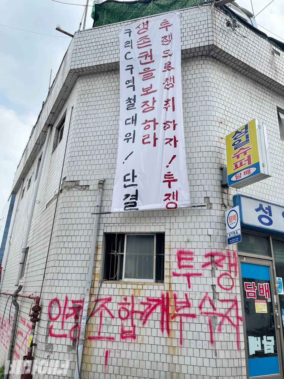 성일장 여관 건물에 철거민이 내건 현수막. ‘구리C구역 철대위! 단결, 생존권을 보장하라, 투쟁으로 쟁취하자! 투쟁’이라고 적혀 있다. 현수막 아래 외벽에는 빨간색으로 ‘투쟁, 인창조합 깨부수자’라고 쓰여 있다. 사진 하민지