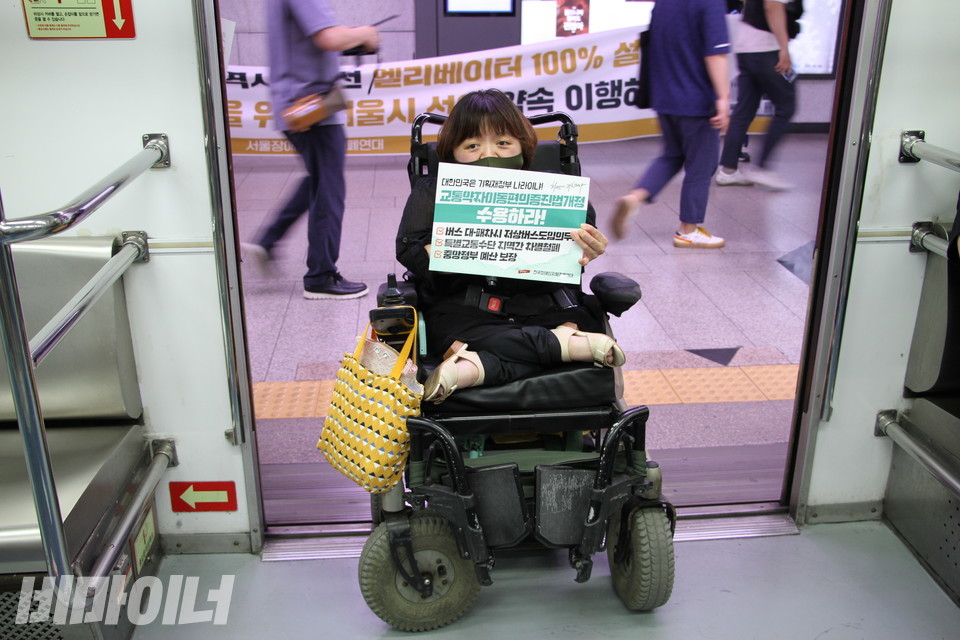 한 장애인 활동가가 ‘교통약자이동편의증진법개정 수용하라’라고 적힌 피켓을 들고 지하철 타기 투쟁을 하고 있다. 사진 이가연