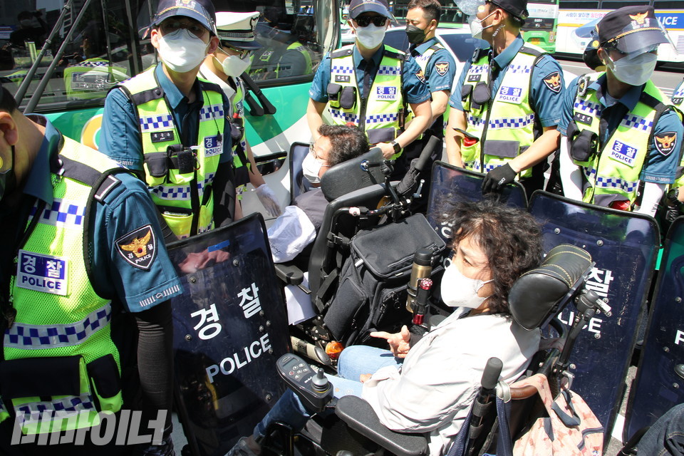 서울시청 앞 도로에서 장애인 활동가들이 버스를 막아서고 있고 경찰들이 이를 저지하고 있다. 사진 이가연