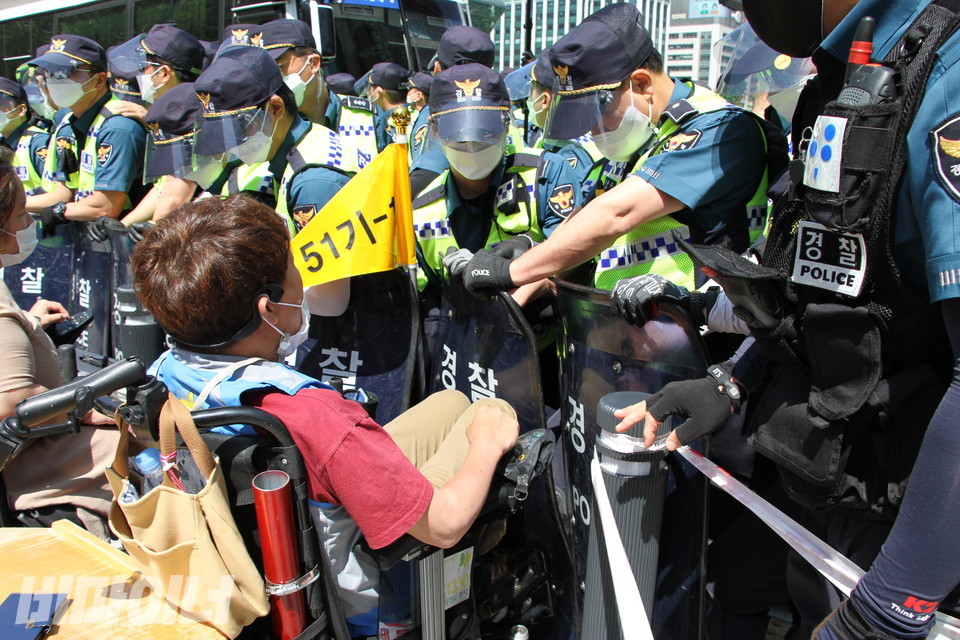 경찰들이 서울시청 앞에서 버스를 타려고 횡단보도를 건너려는 장애인을 저지하고 있다. 사진 이가연