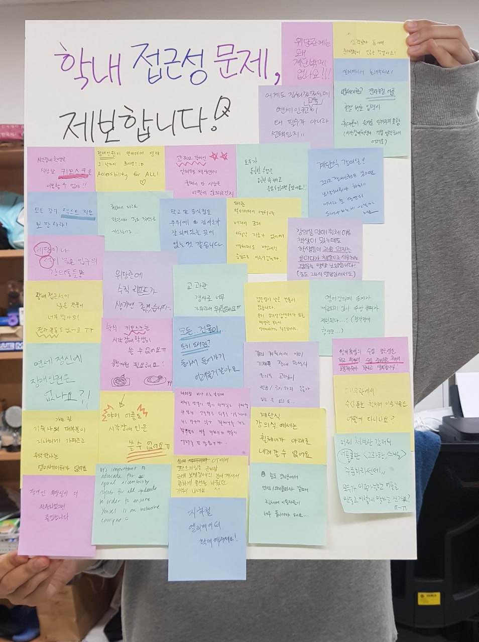 커다란 판넬에 수십 개의 알록달록한 포스트잇이 붙어 있다. 판넬 위에는 “학내 접근성 문제, 제보합니다!”라는 문구가 적혀 있다. 출처 연세대학교 장애인권동아리 게르니카 페이스북