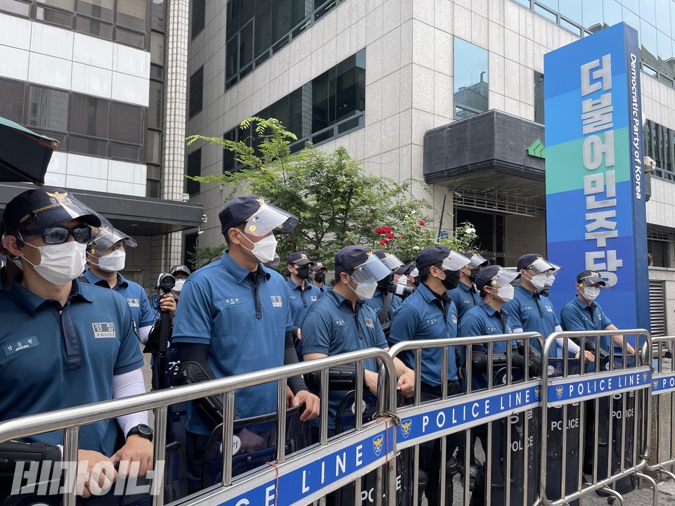 민주당 당사 정문 앞을 지키는 경찰 수십 명들. 쇠창살 모양의 폴리스 라인이 처져 있다. 사진 하민지