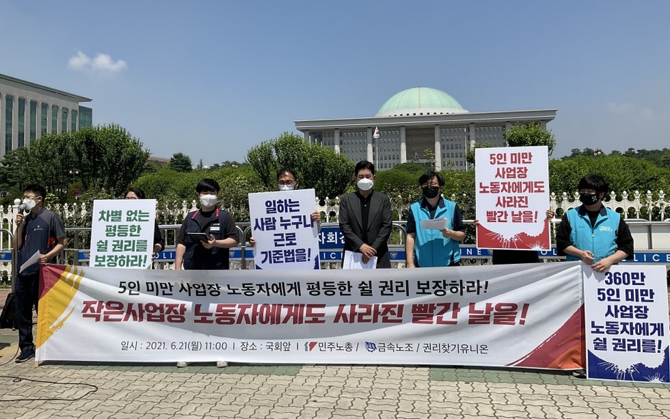 권리찾기유니온 등 시민사회단체의 기자회견 현장. 활동가들이 ‘차별 없는 평등한 쉴 권리를 보장하라!’, ‘일하는 사람 누구나 근로기준법을!’, ‘360만 5인 미만 사업장 노동자에게 쉴 권리를!’ 등의 문구가 적힌 피켓을 들고 서 있다. 현수막에는 ‘작은 사업장 노동자에게도 사라진 빨간 날을!’이라 적혀 있다. 사진 권리찾기유니온