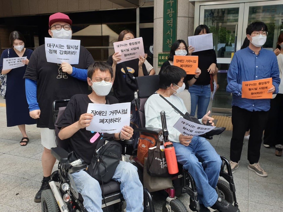 기자회견 참가자들이 손팻말을 들고 있다. 손팻말에는 '대구시는 탈시설 정책 강화라!', '장애인 거주시설 폐지하라!', '대구시는 중앙정부 탈시설 사업에 참여하라!' 등이 써 있다. 사진 대구장애인차별철폐연대