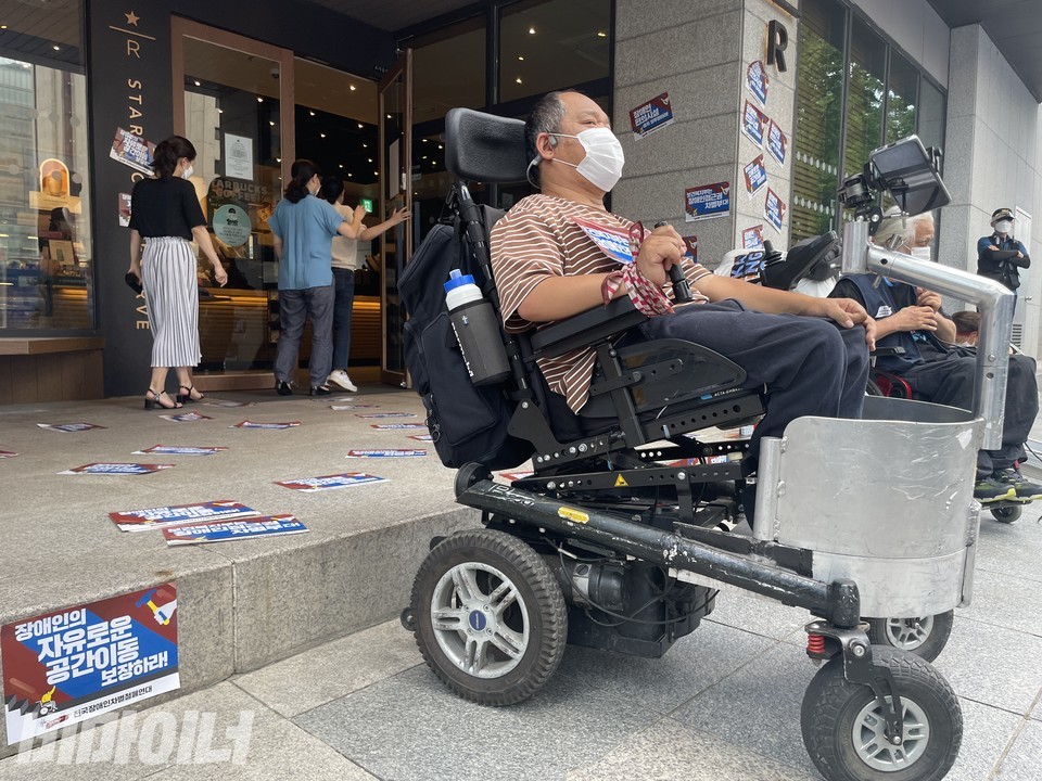 이규식 서울장차연 대표 뒤로 비장애인들이 스타벅스 매장을 들어가고 있다. 사진 하민지