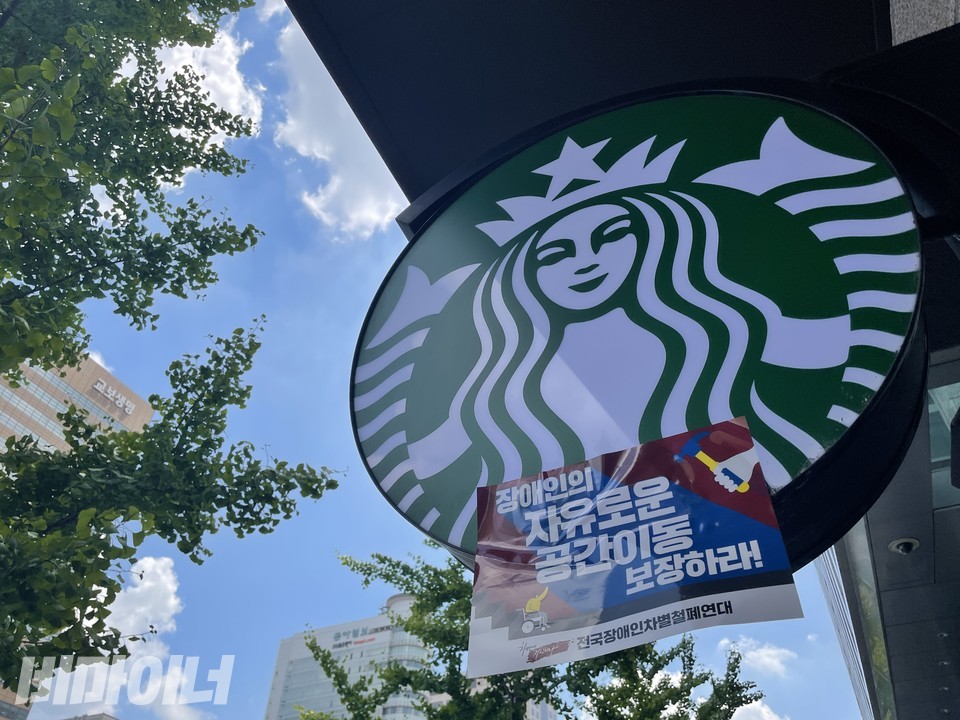 스타벅스 간판에 ‘장애인의 자유로운 공간이동 보장하라’라고 적힌 피켓이 붙어 있다. 사진 하민지