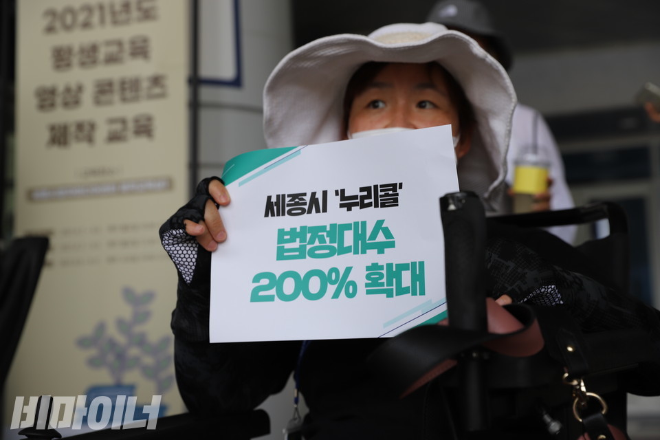 휠체어를 이용하는 한 활동가가 ‘세종시 누리콜 법정대수 200% 확대’라고 적힌 피켓을 들고 있다. 사진 하민지