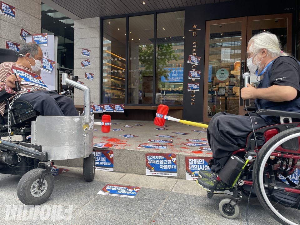 지난 7월 29일, 이규식 서울장차연 상임대표와 박경석 전장야협 이사장이 뿅망치 끝에 빨간 물감을 묻혀 스타벅스 매장 앞 턱을 내리치고 있다. 사진 하민지