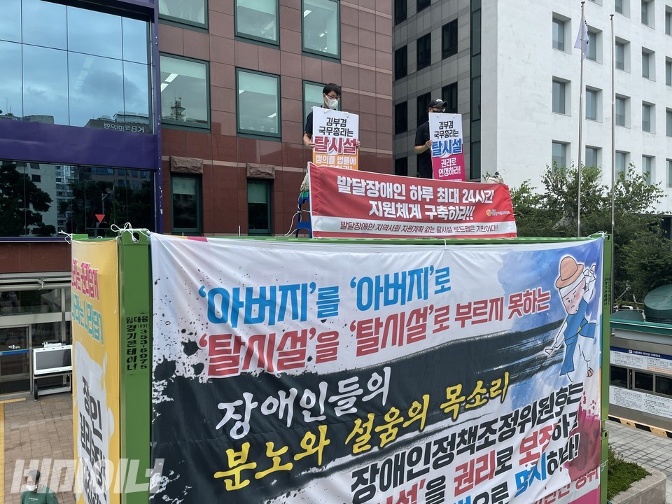 탈시설로드맵이 발표되는 지난 2일, 발달장애 자녀를 둔 부모들이 이룸센터 앞 컨테이너 옥상에 올라 정부에 제대로된 탈시설로드맵 정책을 촉구했다. 사진 하민지