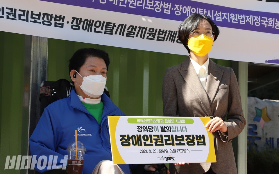 최용기 한국장애인자립생활센터협의회 회장(왼쪽)과 장혜영 정의당 의원이 ‘정의당이 발의합니다. 장애인권리보장법’이라고 적힌 피켓을 들고 있다. 사진 하민지