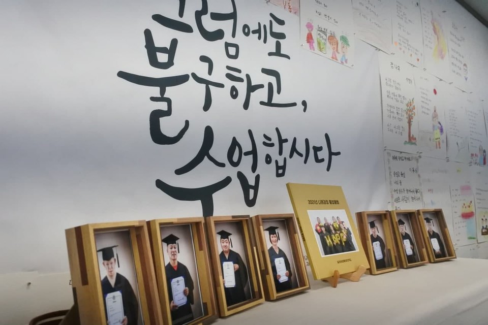 질라라비야학에 초등학력인정 문해교육과정 졸업자들의 사진이 전시돼 있다. 뒤로는 ‘그럼에도 불구하고 수업합시다’라는 플랜카드가 걸려 있다. 사진 질라라비야학