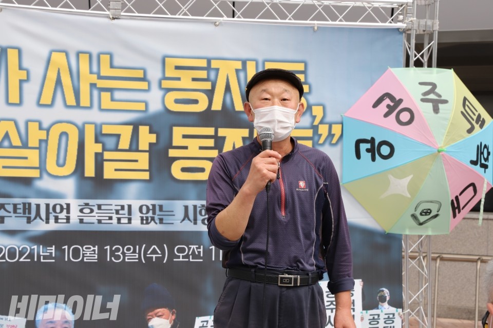 김정호 사랑방마을주민동회 이사장이 발언을 하고 있다. 오른편에 '공공주택확대'라고 적혀있는 우산이 보인다. 사진 이가연