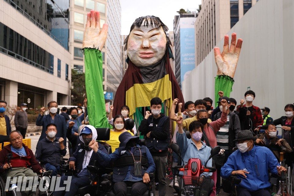 기자회견 참여자들이 민주당사 앞에서 거대한 조형물과 함께 투쟁을 외치고 있다. 사진 이가연