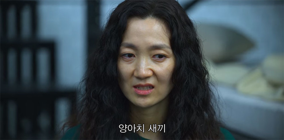 길고 부스스한 머리의 미녀는 덕수 패거리가 가는 방향을 눈으로 따라가며 다문 이빨이 살짝 드러날 만큼 입 주변을 찡그린다. "양아치 새끼"라는 대사가 나오고 있다. 넷플릭스 화면 캡쳐.