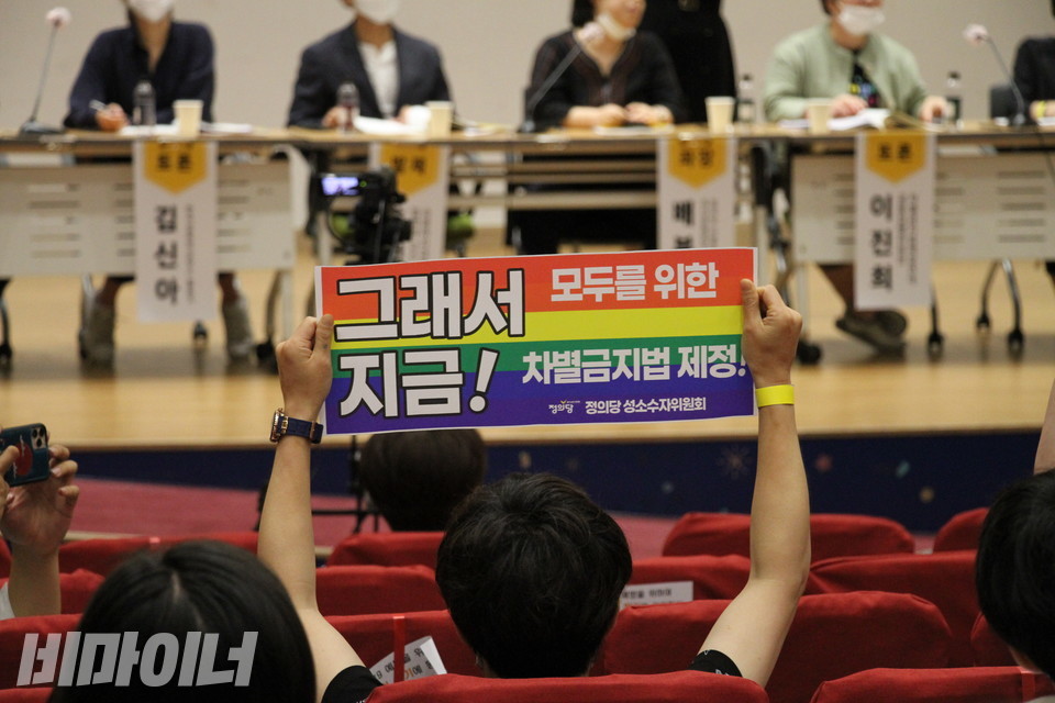 지난해 7월, 장혜영 정의당 국회의원실의 주관으로 ‘포괄적 차별금지법 제정을 위한 국회 토론회’가 여의도 국회의원회관 대회의실에서 열렸다. 한 활동가가 '그래서 지금! 모두를 위한 차별금지법 제정!'이라고 적힌 무지개색 손피켓을 들고 있다. 사진 이가연
