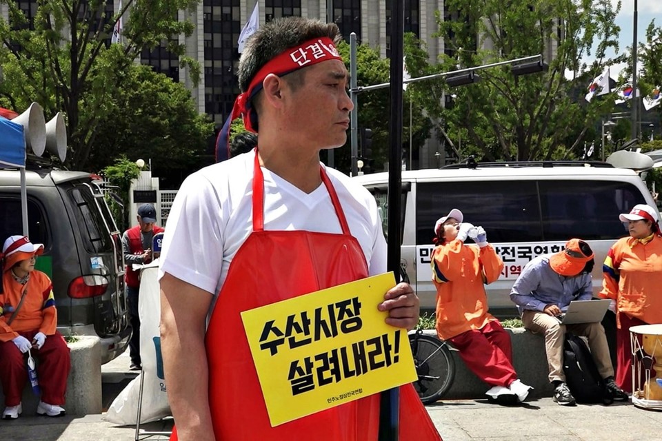 투쟁 중인 나세균. ‘단결’이라 적힌 빨간 머리띠를 둘렀다. ‘수산시장 살려내라!’라고 적힌 피켓을 들고 있다. 사진 은석