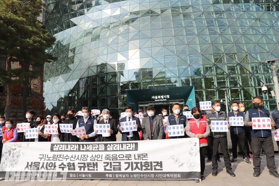 50여 명의 구 시장 상인들, 활동가들이 기자회견을 열고 있다. 현수막에 ‘살려내라! 나세균을 살려내라! 구 노량진수산시장 상인 죽음으로 내몬 서울시와 수협 규탄! 긴급 기자회견’이라 적혀 있다. 사진 하민지