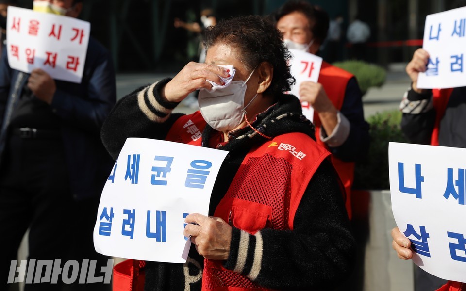 한 상인이 ‘나세균을 살려내라’라고 적힌 피켓을 들고 눈물을 훔치고 있다. 사진 하민지