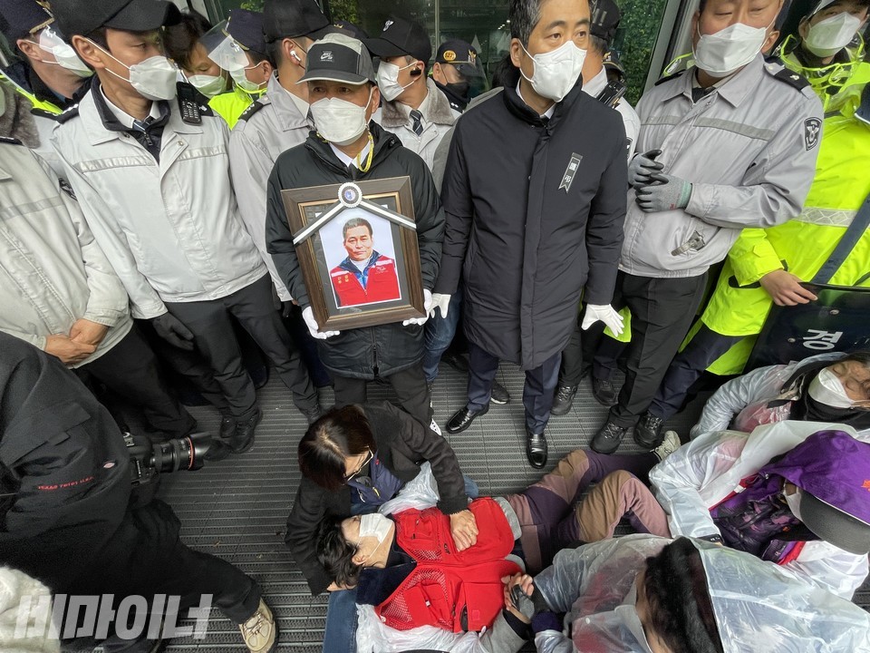 나세균 열사 영정을 들고 있는 한상범 공동지역장. 상인 한 명이 바닥에 쓰러져 있다. 경찰 수십 명이 시청 정문 앞을 막으며 상인들을 진압했다. 사진 하민지
