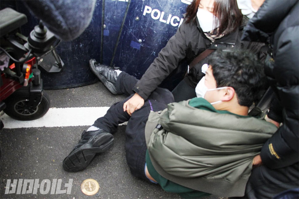 쓰러진 휠체어에서 빠져나온 유재근 활동가를 다른 활동가들이 부축하고 있다. 사진 강혜민
