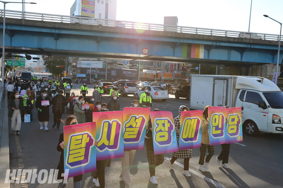 활동가들이 ‘탈시설장애인당’이 한 글자씩 적힌 커다란 피켓을 들고 행진하고 있다. 사진 하민지