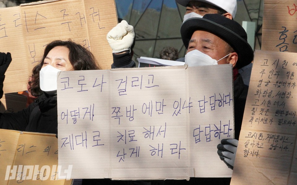 기자회견 현장. 쪽방 주민이 “코로나 걸리고 어떻게 쪽방에만 있냐, 제대로 치료해서 낫게 해라. 답답하다, 답답하다”라고 적은 피켓을 들고 ‘투쟁’을 외치고 있다. 사진 하민지