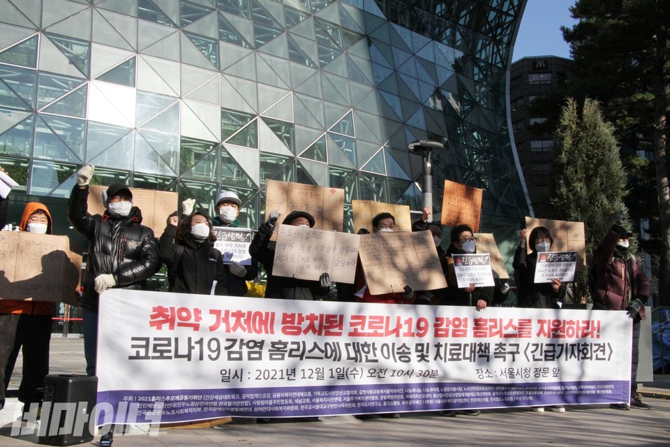 홈리스 당사자와 활동가들이 서울시청 앞에서 기자회견을 열고 있다. 현수막에는 ‘취약 거처에 방치된 코로나19 감염 홈리스를 지원하라! 코로나19 홈리스에 대한 이송 및 치료대책 촉구’라고 적혀 있다. 사진 하민지