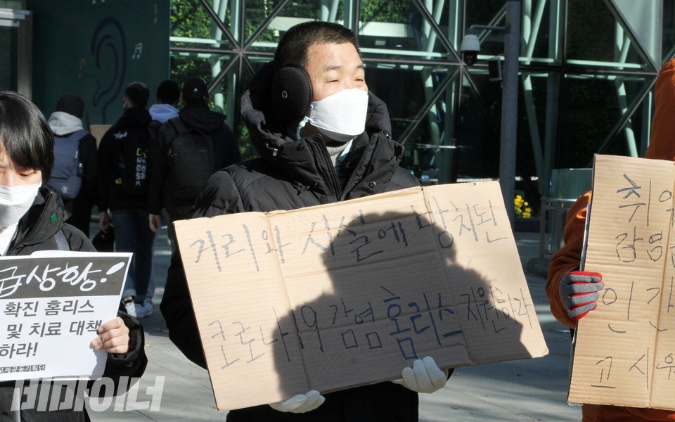 기자회견 참가자가 ‘거리와 시설에 방치된 코로나19 감염 홈리스 지원하라’라고 적힌 피켓을 들고 있다. 사진 하민지