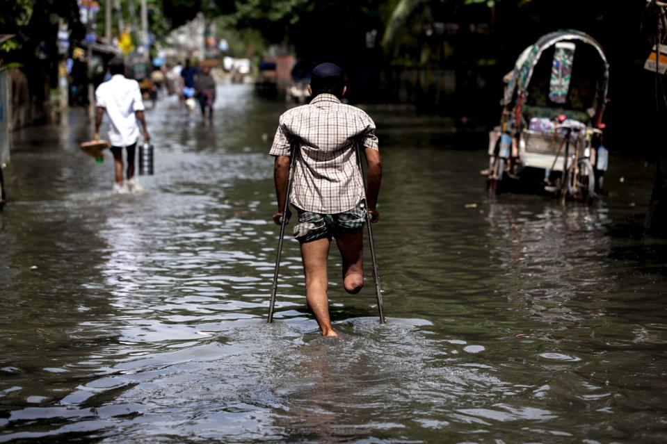 침수된 도로 위를 목발 짚은 사내가 걸어가고 있는 뒷모습이 보인다. 그는 오른쪽 무릎 아래가 없다. 사진 유엔