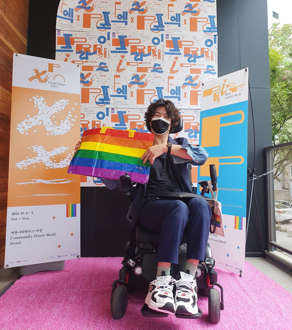 유진우 활동가의 모습. 전동휠체어를 탄 유진우 활동가가 무지개로 된 가방을 들어 보이고 있다. 사진 제공 유진우 