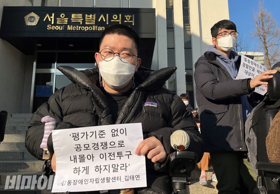 기자회견 참가자가 '평가기준 없이 공모경쟁으로 내몰아 이전투구 하게 하지말라'라는 손피켓을 들고 있다. 사진 허현덕
