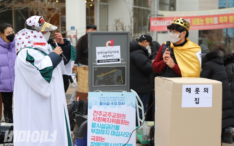 동방박사가 헤롯의집(모형)이라는 장애인거주시설 장에게 “탈시설 아기예수가 오셨으니 시설을 폐쇄하라”라고 말하고 있다. 헤롯은 아기예수를 싫어했던 유대 왕이다. 동방박사들이 아기예수의 탄생을 두고 ‘유대인의 왕이 베들레헴에서 태어났다’고 말하자 헤롯은 화를 내며 사진 하민지