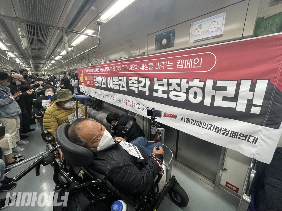 장애인 활동가들이 지하철 한 칸을 점거하고 있다. 열차 내 벽면에 있는 현수막에는 '장애인 이동권 즉각 보장하라'라고 적혀있다. 사진 하민지