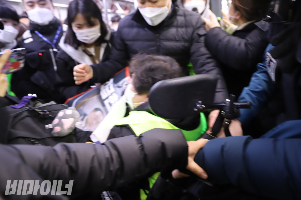 시민과 경찰이 휠체어 이용자의 전동휠체어를 강제로 끌어내고 있다. 사진 허현덕