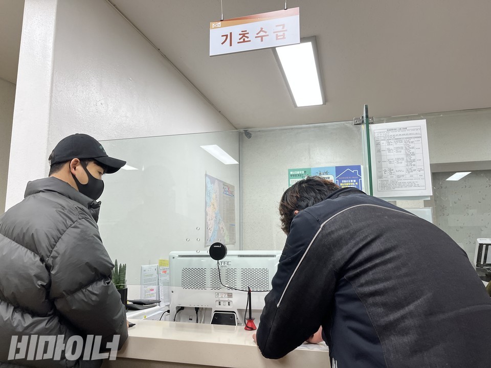 지난 2021년 12월, 박진 씨가 주민센터에서 '가족관계 해체증명서'를 작성하고 있다. 천장에 '기초수급'이라고 적힌 안내판이 달려 있다. 사진 이가연 