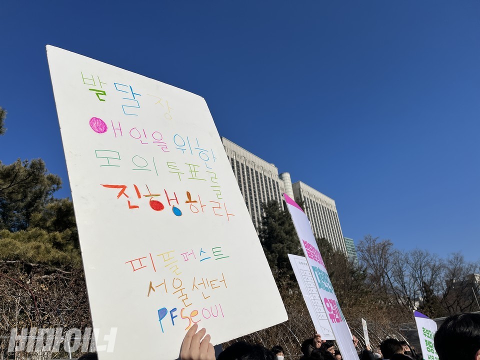 기자회견 참가자가 '발달장애인을 위한 모의투표를 진행하라'라는 피켓을 들어보이고 있다. 뒤편으로 서울중앙지방법원 건물이 보인다. 사진 허현덕