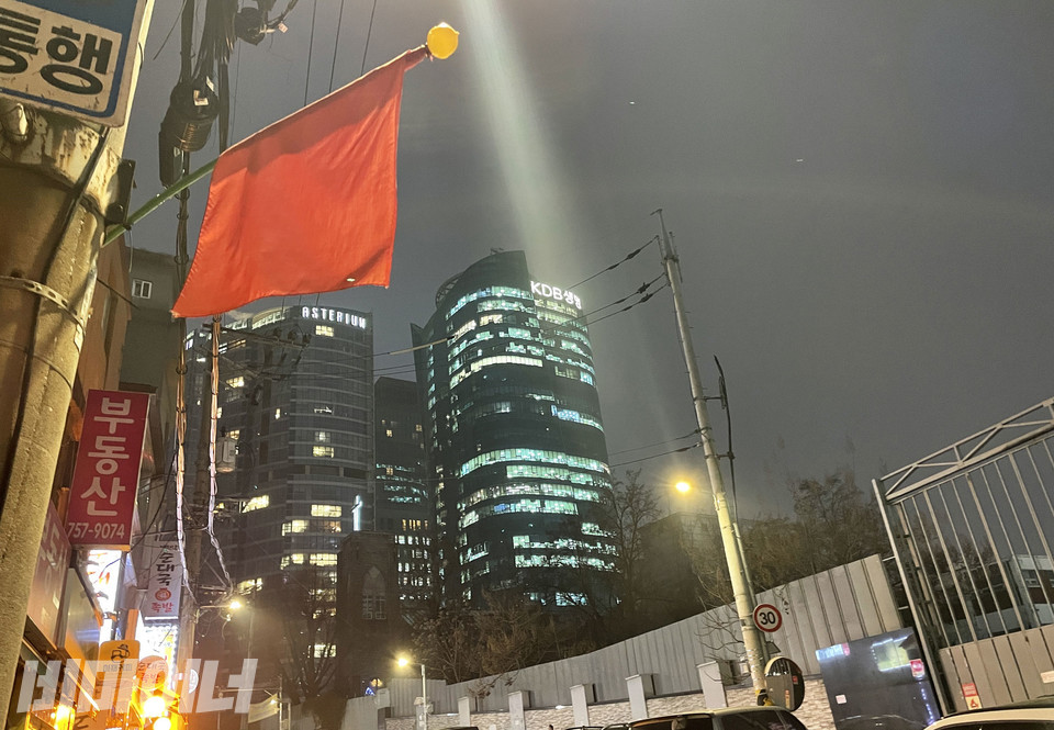 아파트 앞 쪽방촌 건물에 ‘공공개발 반대’를 의미하는 빨간 깃발이 펄럭이고 있다. 사진 하민지