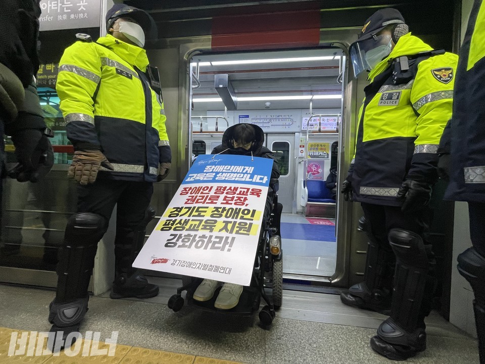 서울역에 도착한 활동가들. 정명호 아람장애인자립생활센터 소장이 열차 출입문을 막고 있다. 목에 ‘장애인에게 교육은 생명입니다, 장애인 평생교육 권리로 보장, 경기도 장애인 평생교육 지원 강화하라!’라고 적힌 피켓을 걸었다. 정 소장 양 옆에 경찰들이 서 있다. 사진 하민지