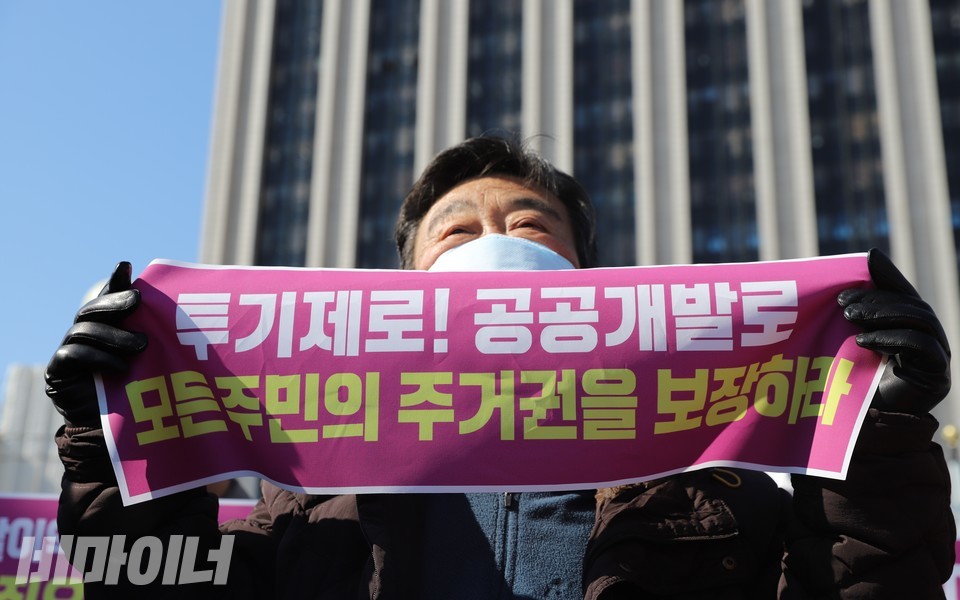 동자동 쪽방주민이 ‘투기제로! 공공개발로 모든 주민의 주거권을 보장하라’라고 적힌 작은 현수막을 펼쳐 보이고 있다. 사진 하민지