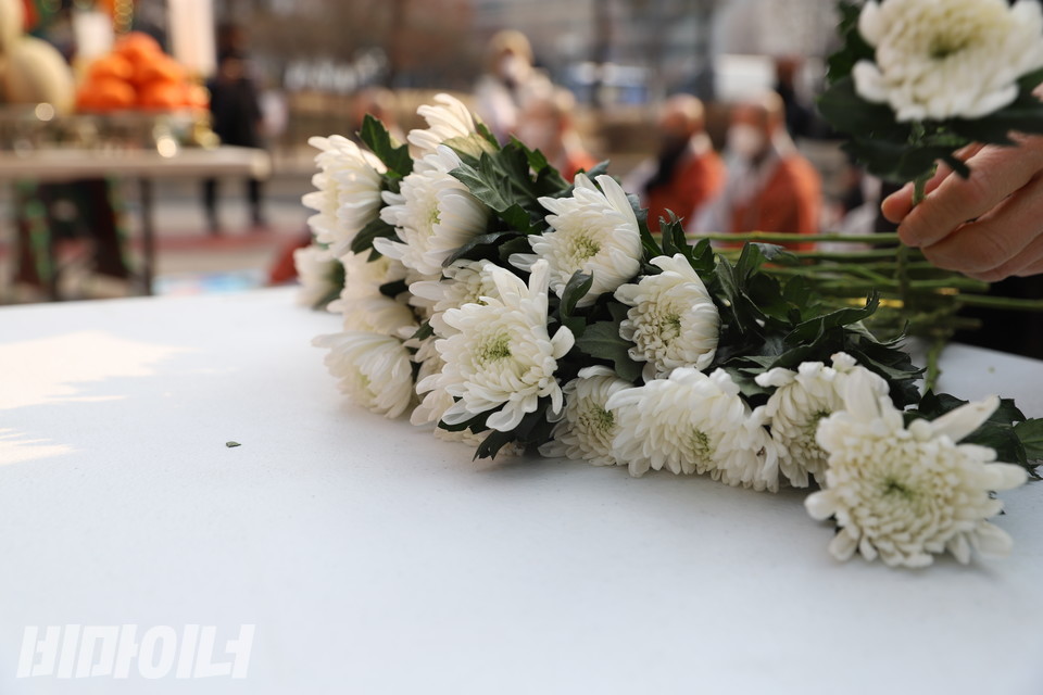 송파 세 모녀를 추모하기 위해 놓은 흰 국화꽃을 추모객이 집어들고 있다. 사진 허현덕