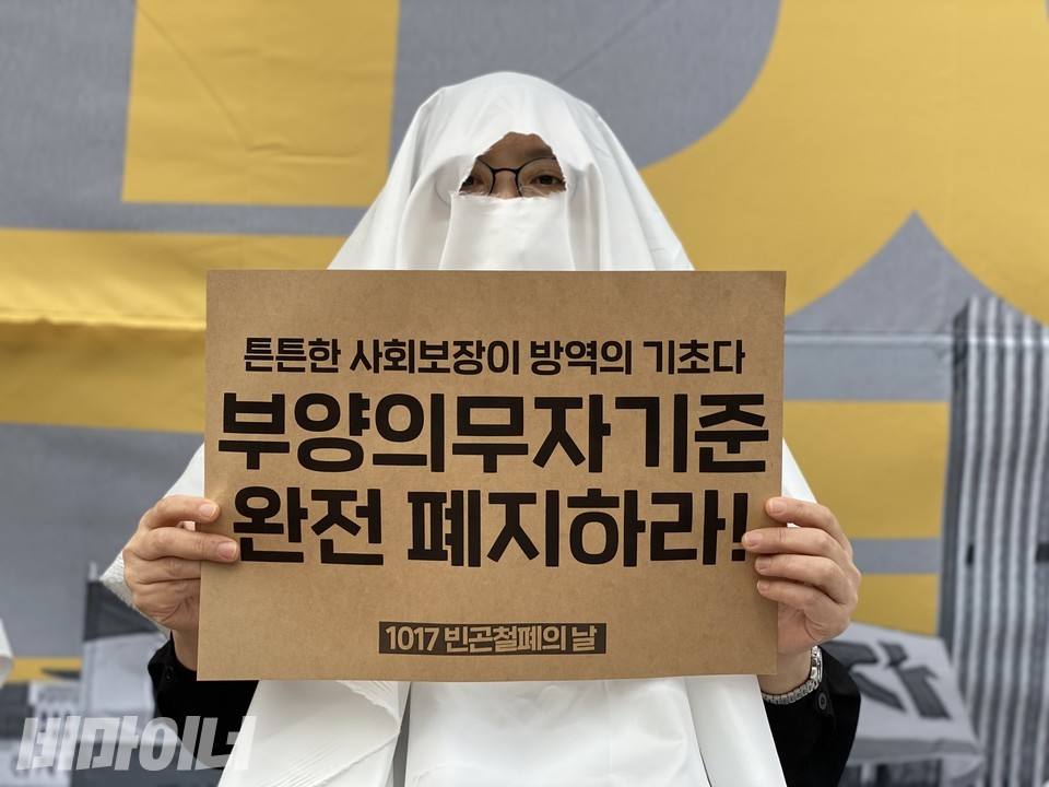 지난해 10월 12일에 열린 1017 빈곤철폐의 날 기자회견 현장. 한 참가자가 ‘든든한 사회보장이 방역의 기초다, 부양의무자기준 완전폐지하라!’라고 적힌 피켓을 들고 있다. 사진 비마이너DB